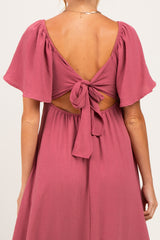 woman wearing a dusty rose maternity dress with flutter sleeves and a tie-back detail