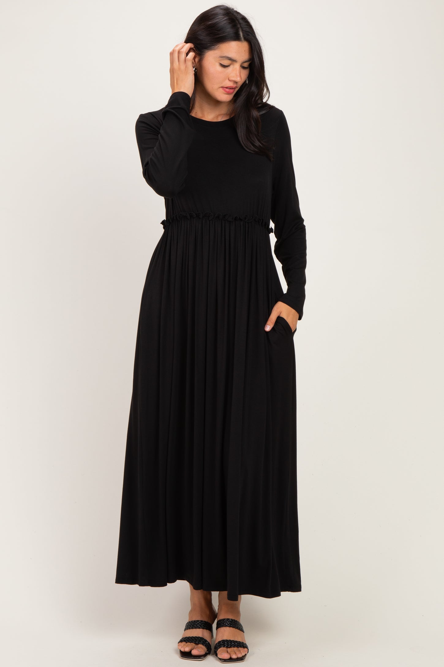 woman wearing a black long sleeve maxi dress with a cinched waist and pockets