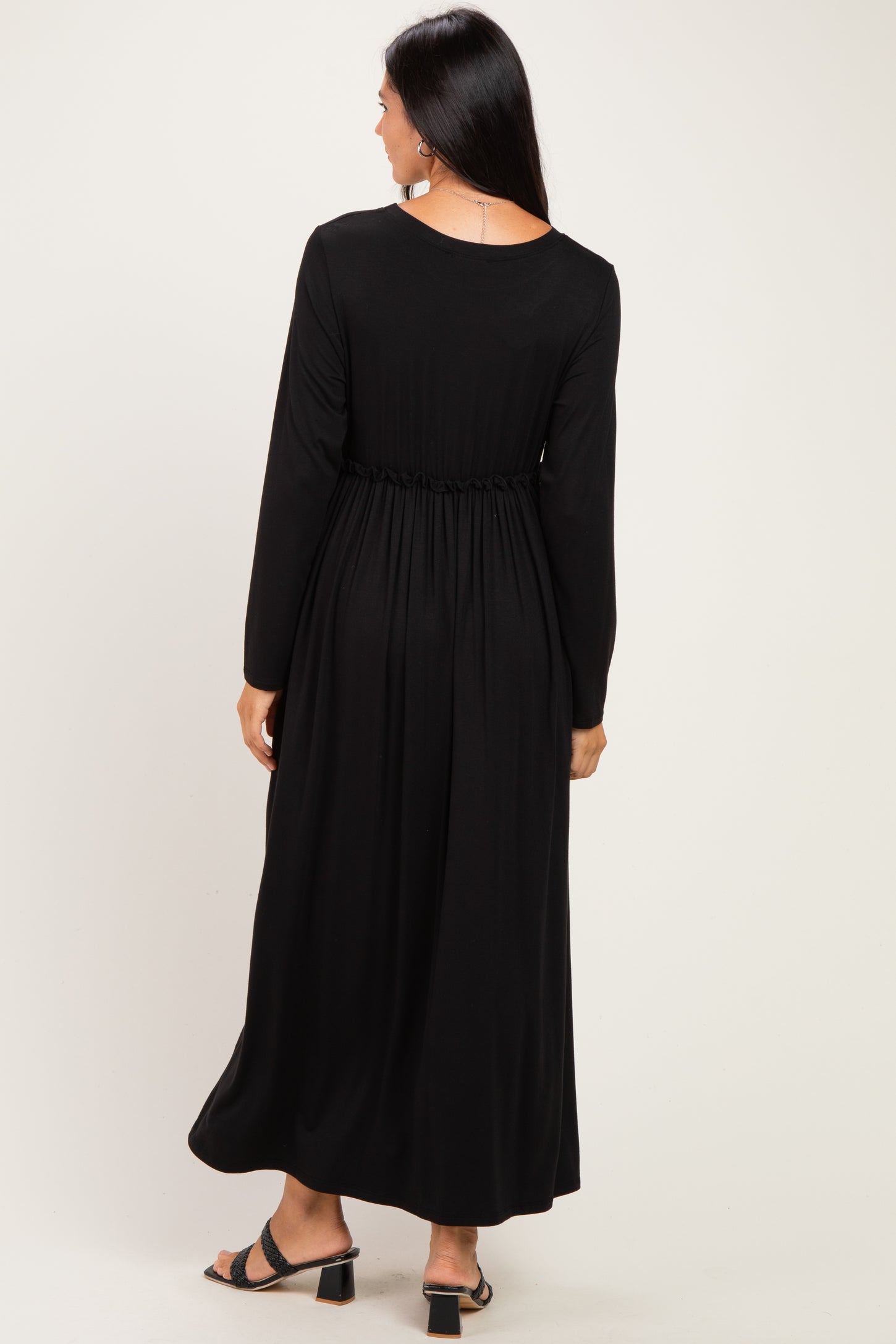 woman wearing a black long sleeve maxi dress with a gathered waist, shown from the back