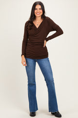 woman wearing a brown long sleeve wrap top paired with flared blue jeans