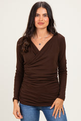 woman wearing a dark brown long sleeve wrap top with ruching details and paired with blue jeans