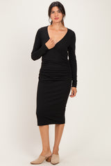 woman wearing a black long sleeve wrap dress with ruched details and a midi length