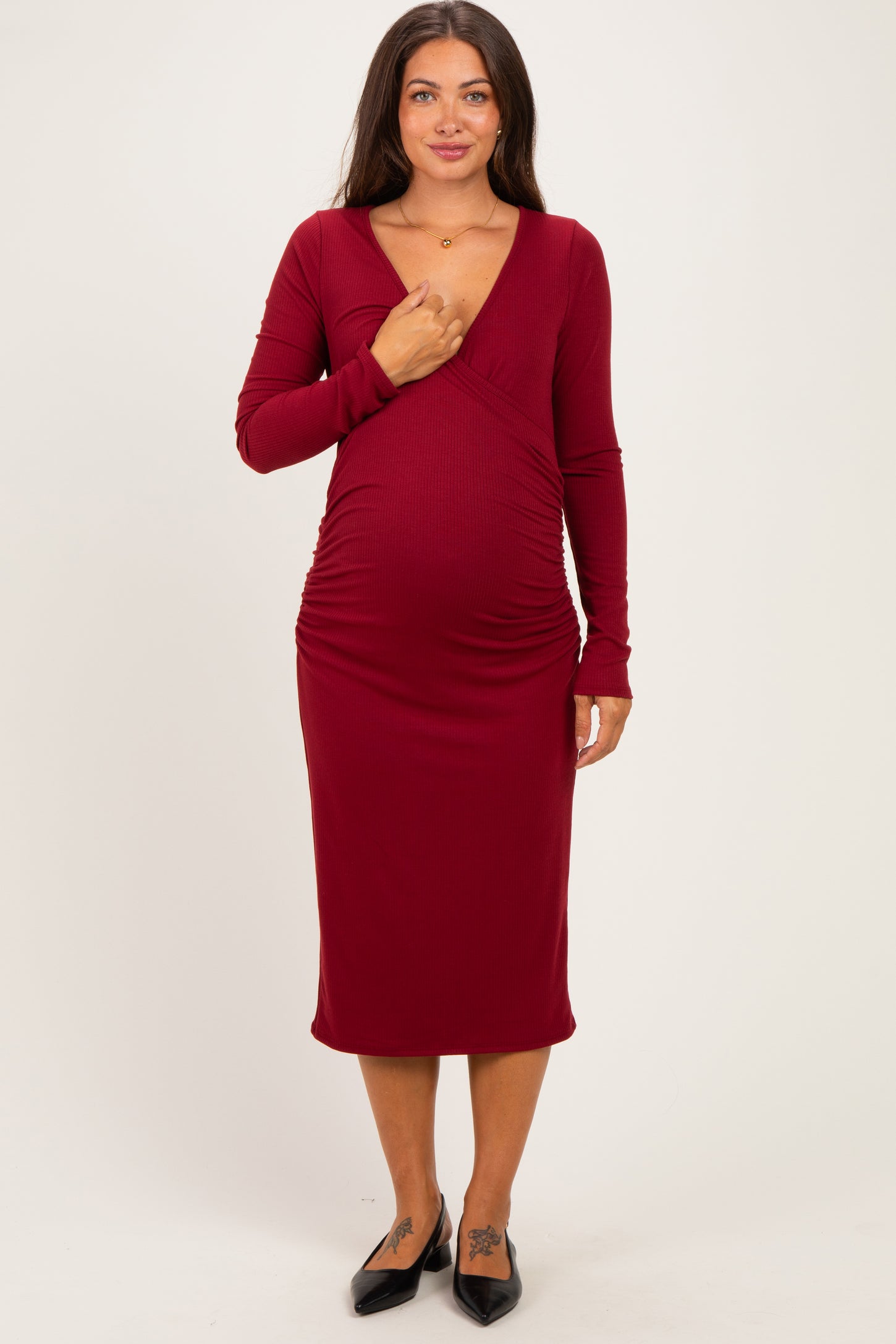 woman wearing a burgundy long sleeve maternity dress that highlights her baby bump