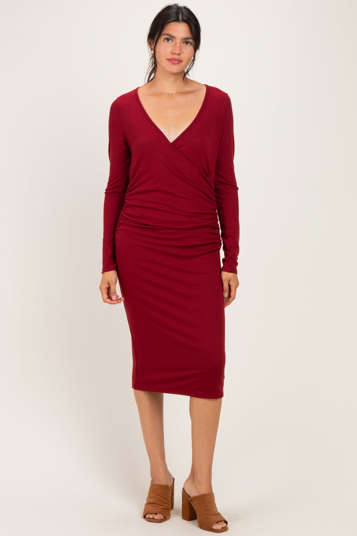 woman wearing a burgundy long sleeve wrap dress with a deep v-neck and ruching at the waist
