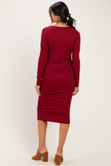 woman wearing a burgundy long sleeve midi dress with a fitted silhouette and back view visible