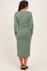 woman wearing a long sleeve green ribbed maternity dress showing her baby bump from behind