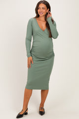 woman wearing a green long sleeve maternity dress with a v-neckline and fitted silhouette, showing her baby bump