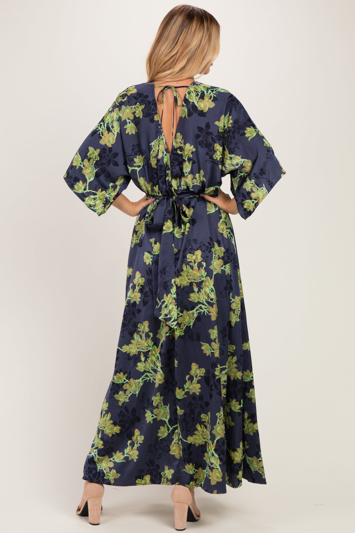 woman wearing a navy floral maxi dress with a tie-back detail and wide sleeves