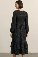 woman wearing a black long sleeve floral print midi dress with a smocked bodice and tiered ruffle hem