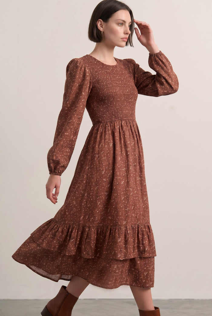 woman wearing a brown floral print midi dress with puff sleeves and a tiered ruffle hem