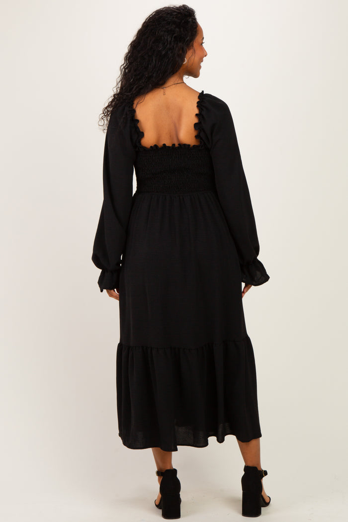 woman wearing a black maternity dress with a smocked bodice and ruffle details on the sleeves and hem