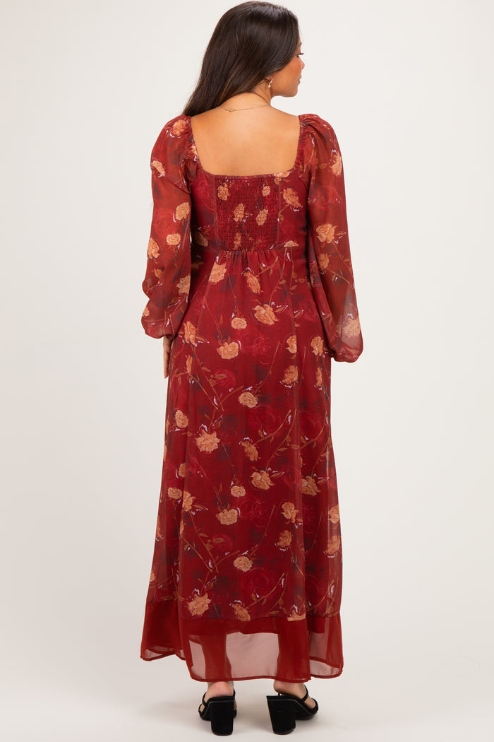 woman wearing a burgundy floral maternity maxi dress with long sleeves and a smocked back design