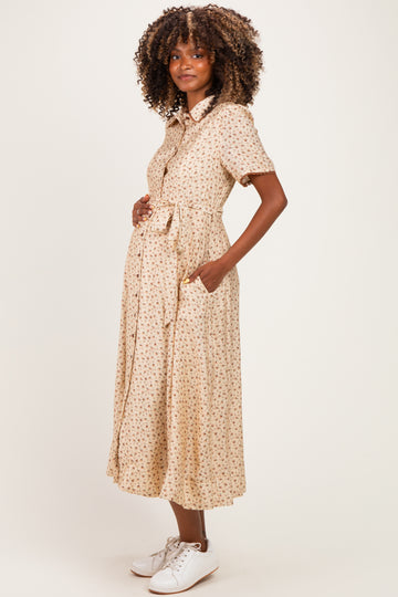 woman wearing a beige floral maternity dress with short sleeves and a tie waist, showing her baby bump