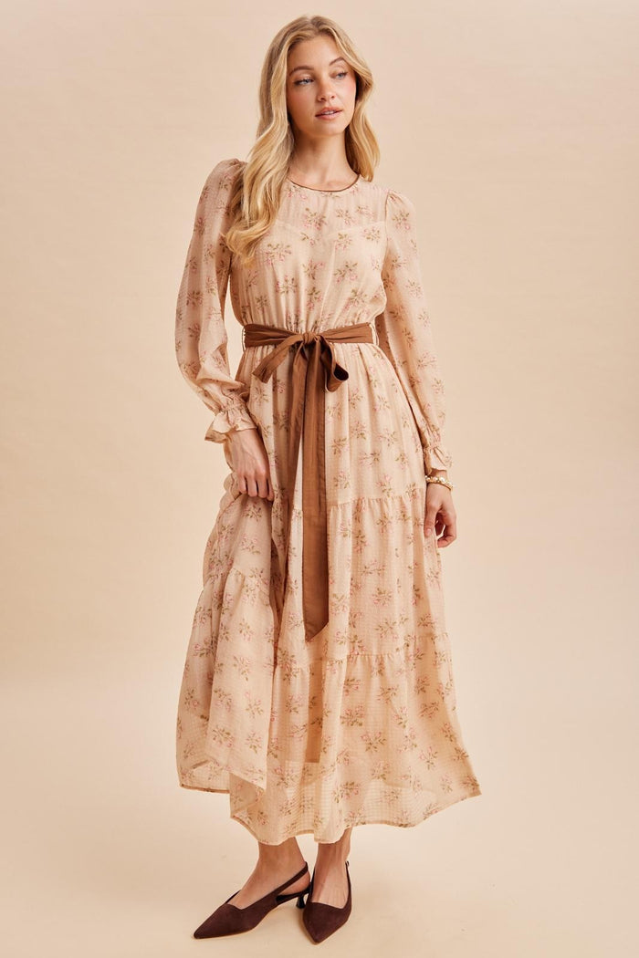 woman wearing a floral printed long sleeve maxi dress with a tied waist belt and pointed toe heels