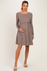 woman wearing a brown striped long sleeve maternity dress and holding her baby bump