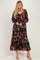 woman wearing a black floral maxi dress with long sleeves and a tie front detail