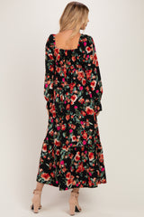 woman wearing a black floral maxi dress with long sleeves and a square back, standing and facing away from the camera