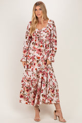 woman wearing a pink floral maxi dress with long sleeves and a square neckline, posing with one hand on her hip