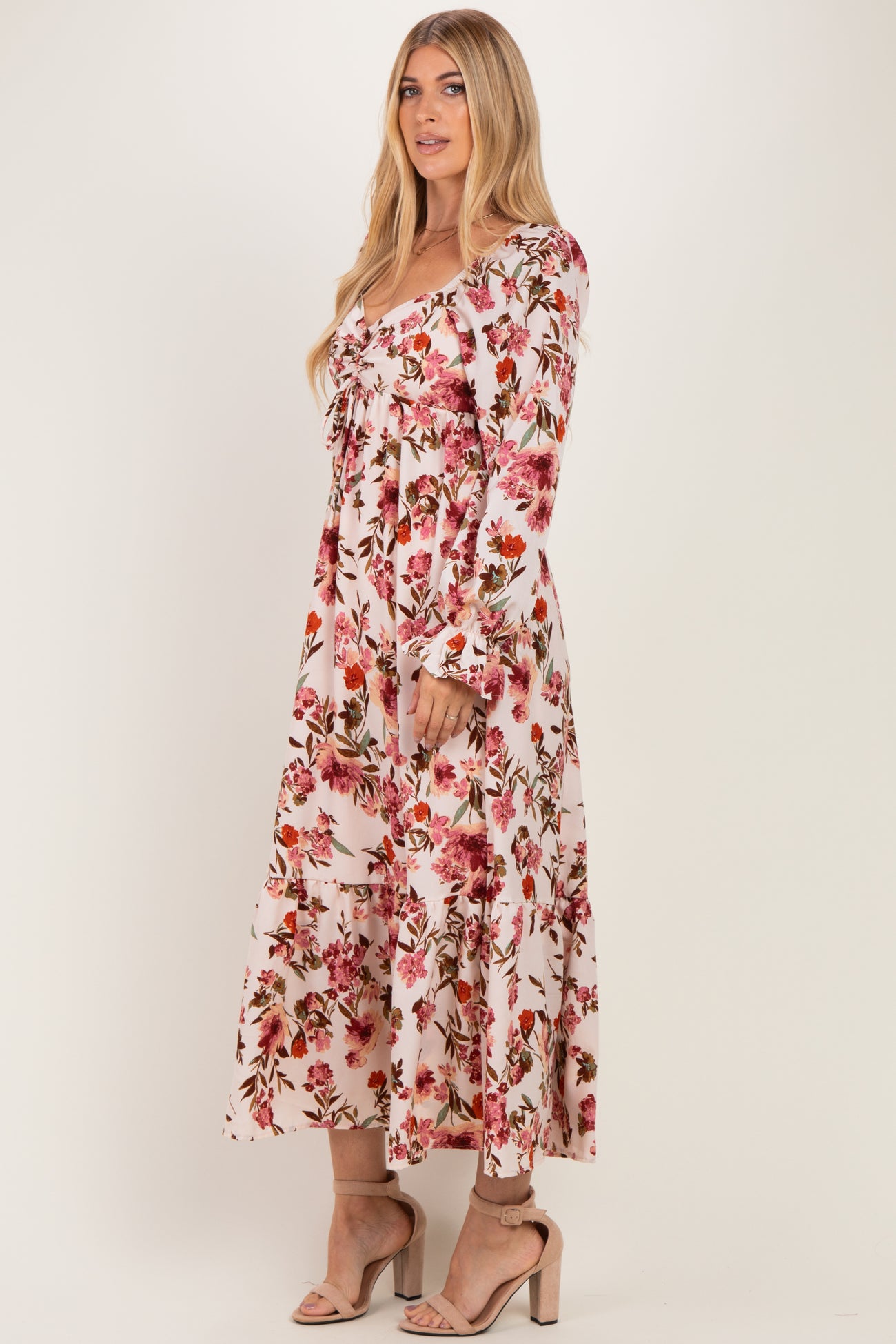 woman wearing a long pink floral maxi dress with long sleeves and a tiered skirt