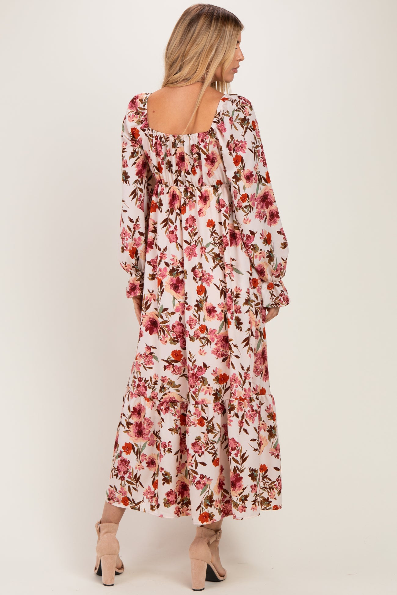 woman wearing a pink floral maxi dress with long sleeves and a square neckline, seen from the back