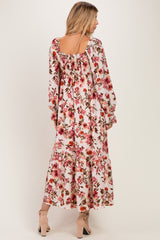 woman wearing a pink floral maxi dress with long sleeves and a square neckline, seen from the back