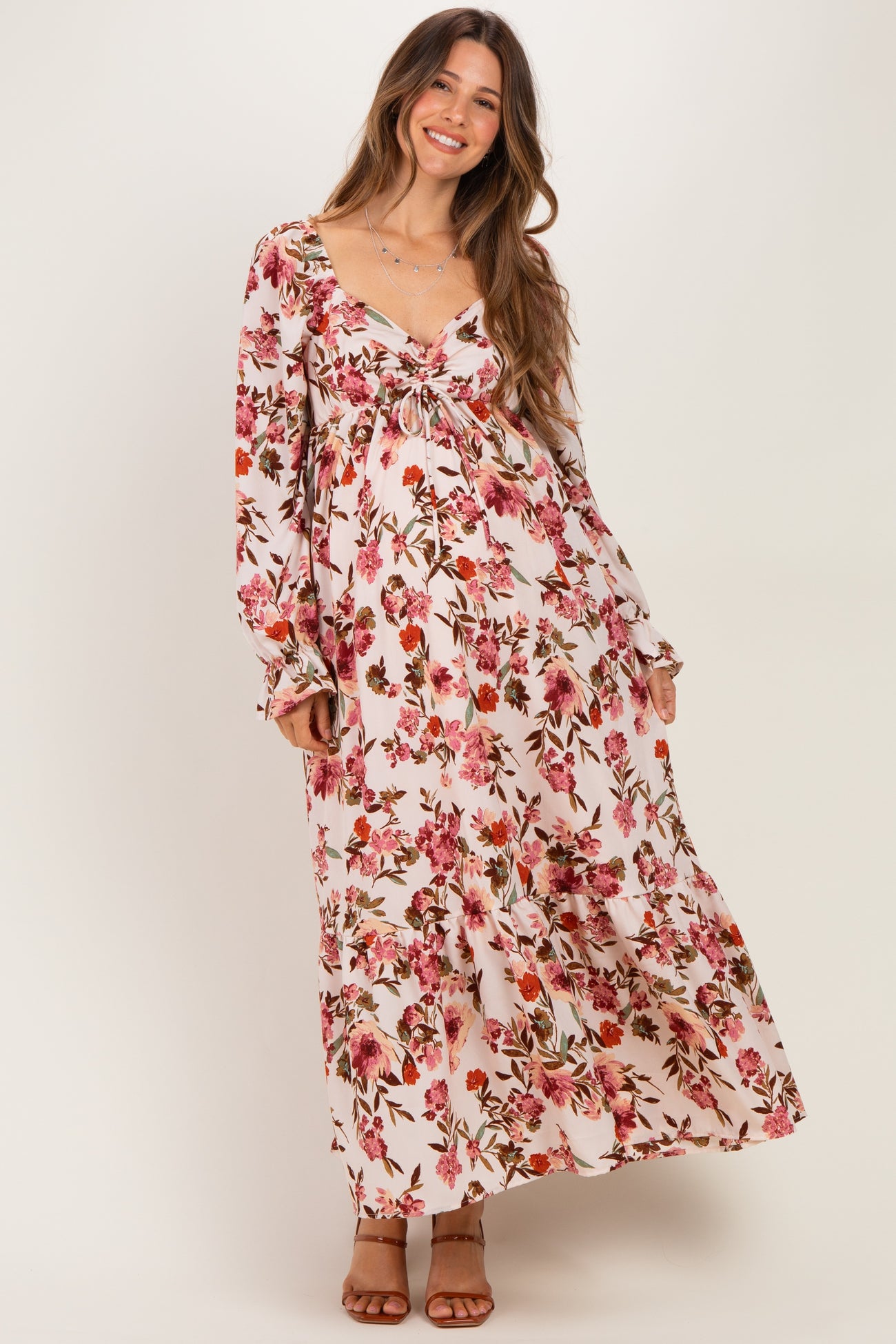 woman wearing a floral maxi maternity dress with a tie front and long sleeves, showcasing her baby bump