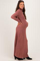 woman wearing a rust long sleeve ribbed maxi dress with a fitted bodice and a flowing skirt, showing her baby bump