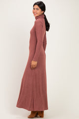 woman wearing a long dusty rose turtleneck maxi dress with long sleeves and a fitted silhouette