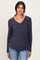 woman wearing a navy long sleeve v-neck top with ruching details and jeans