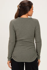 woman wearing a dark green maternity long sleeve top with gathering at the back