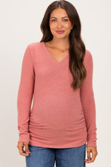 woman wearing a pink maternity long sleeve top with a v-neck and a visible baby bump