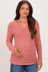 woman wearing a rose pink long sleeve maternity top with a v-neck and a visible baby bump