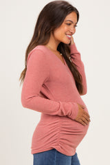 woman wearing a pink long sleeve maternity top with ruching, showing her baby bump