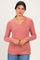 woman wearing a rose pink long sleeve v-neck top with gathered sides and a relaxed fit