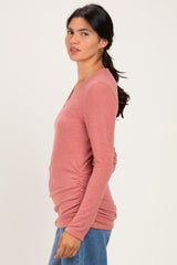 woman wearing a pink long sleeve fitted top with side ruching and a v-neckline styled with jeans