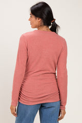 woman wearing a pink long sleeve top with gathered detailing at the back paired with blue jeans