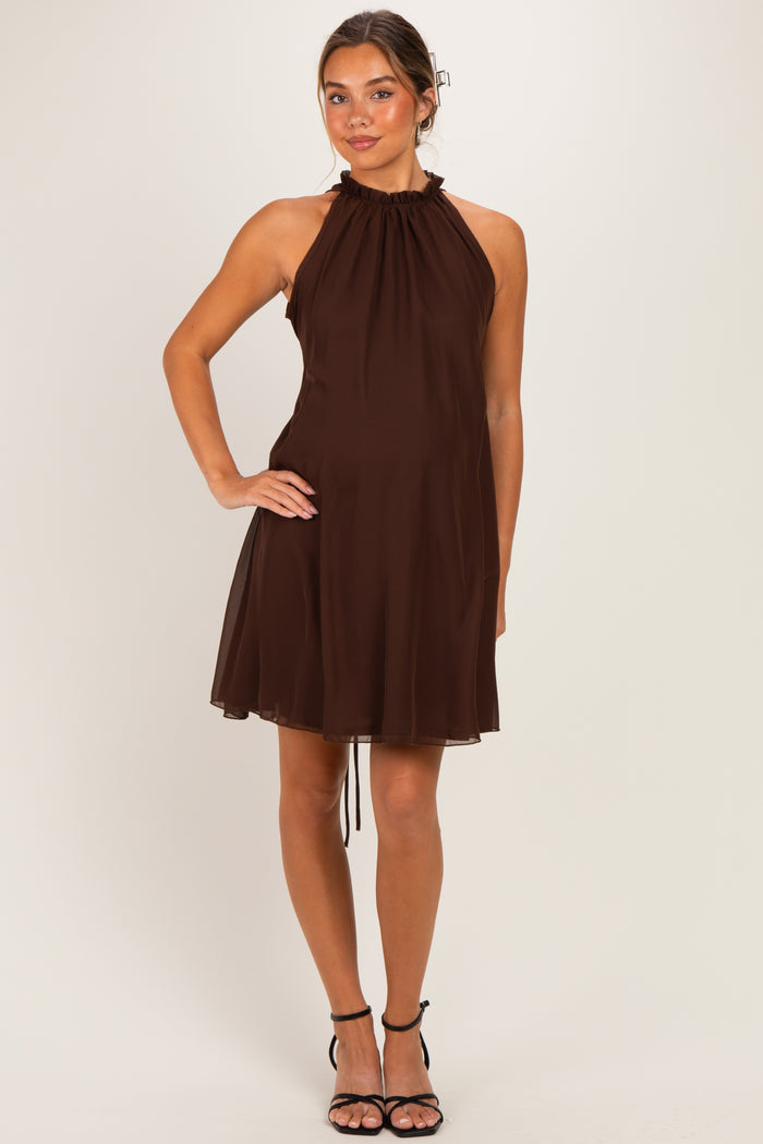 woman wearing a brown halter maternity dress with a flowing silhouette and a gathered neckline, showing her baby bump