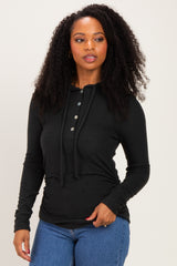 woman wearing a black long sleeve hoodie with buttons and a drawstring, paired with blue jeans