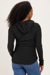 woman wearing a black long sleeve hooded top, showing gathered detailing at the back
