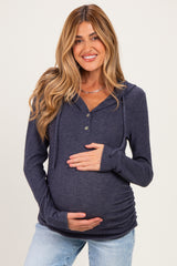 woman wearing a navy blue maternity hoodie with a button-up front and ruched sides, holding her baby bump