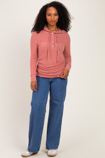 woman wearing a rose pink long sleeve henley top with a hood and light blue wide leg jeans