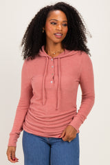 woman wearing a rust pink long sleeve hooded henley top with three buttons and drawstring details