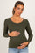 woman wearing an olive green long sleeve maternity top with a scalloped neckline and holding her baby bump