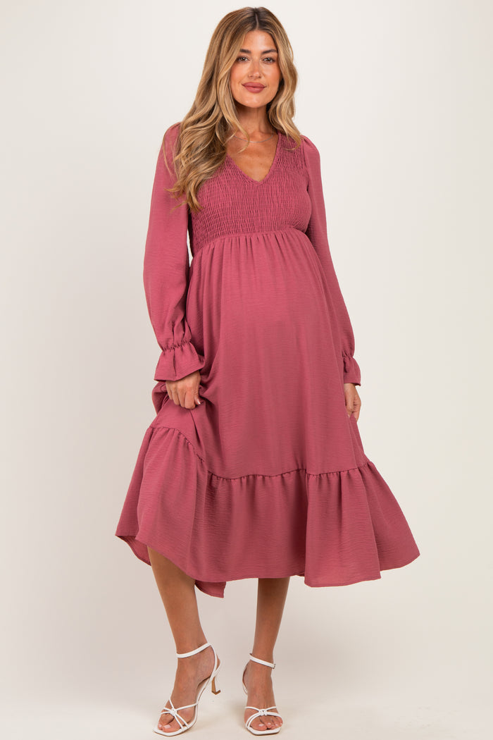 woman wearing a dusty rose maternity dress with a smocked bodice and tiered skirt, showcasing her baby bump