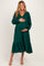 woman wearing a green maternity dress with long sleeves and a ruffled hem, holding her baby bump