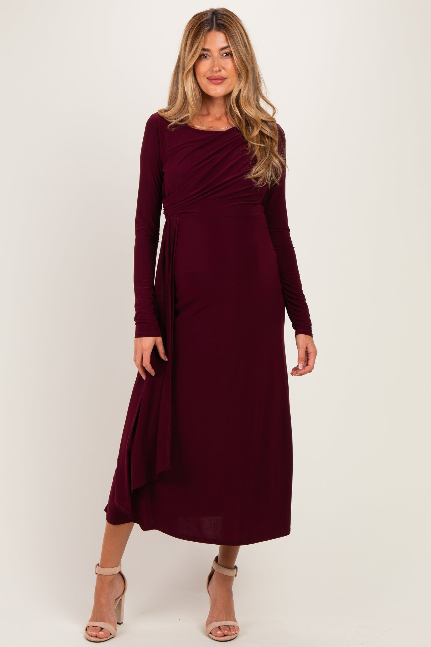 woman wearing a burgundy long sleeve maternity dress with a wrap design and flowing skirt
