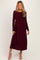woman wearing a burgundy long sleeve maternity dress with a wrap design and flowing skirt