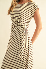 woman wearing a beige and brown striped dress with a knotted detail at the waist and short cap sleeves