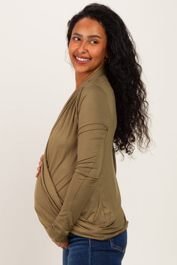 woman wearing an olive green wrap maternity top and holding her baby bump