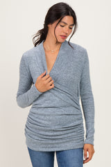 woman wearing a blue wrap-style long sleeve top with ruching details paired with jeans